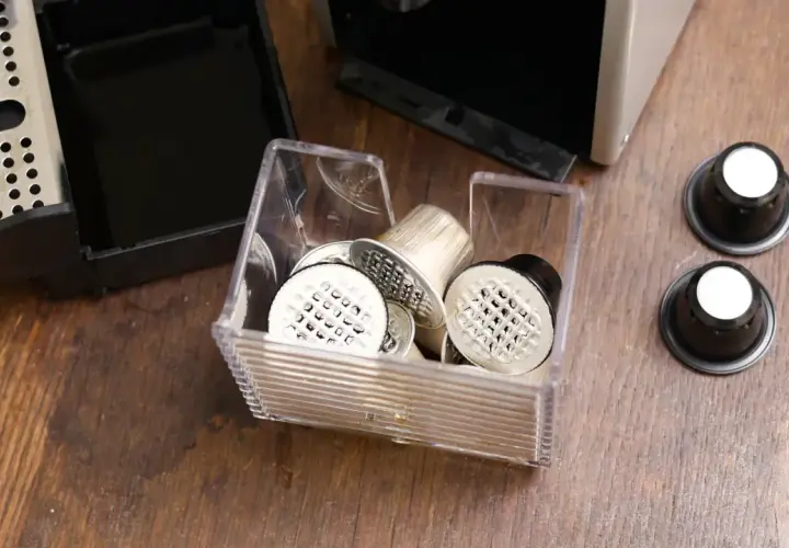 Pojemnik z kapsułkami do Nespresso, obok ekspresu i tacki na zużyte kapsułki. Czas na odkamienianie!
