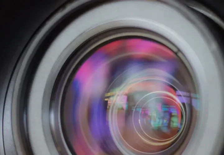 Widok soczewki obiektywu z kolorowymi refleksami, ukazujący aberrację sferyczną.