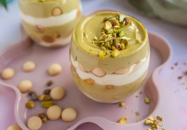 Pyszny deser w pucharku: krem pistacjowy z mascarpone, przełożony biszkoptami i posypany pistacjami.