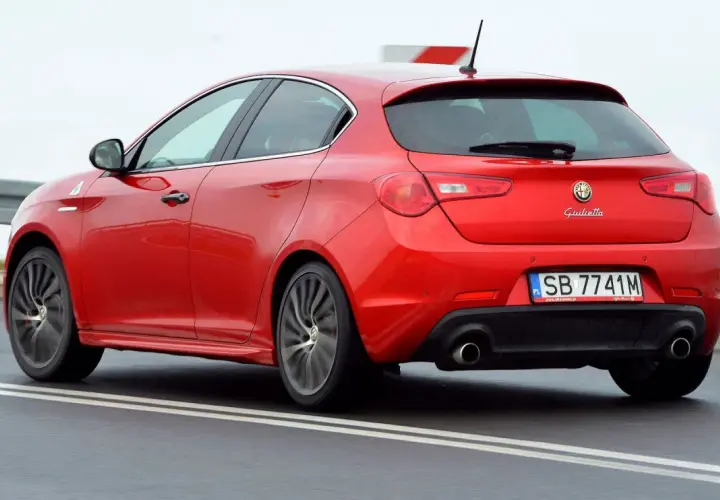 Czerwona Alfa Romeo Giulietta w ruchu. Wiele osób szuka alfa romeo giulietta opinie, by poznać wrażenia z jazdy tym modelem.