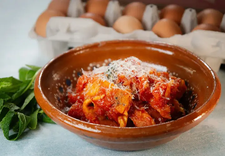 Frittata in trippa, un piatto saporito con uova e trippa in salsa di pomodoro, guarnito con parmigiano.