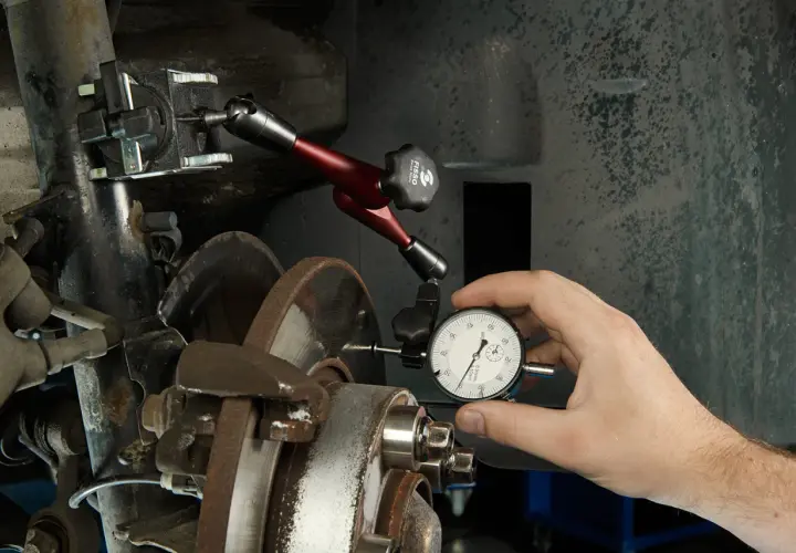 Mechanik mierzy bicie tarczy hamulcowej, by wyeliminować szarpanie przy hamowaniu.