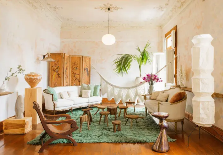 A serene boho space with a white sofa, macrame hammock, and eclectic decor.