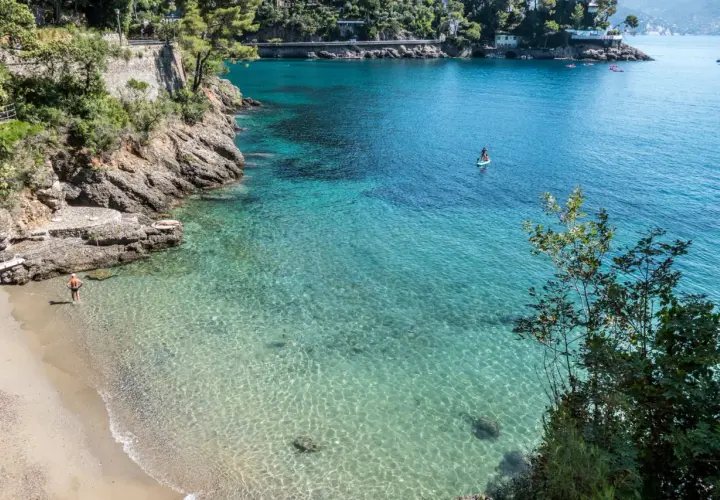Un homme profite de ses vacances à Portofino, se baignant dans les eaux cristallines. Une personne fait du paddleboard au loin.