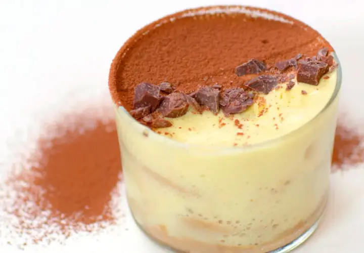 Delizioso tiramisù fatto in casa in un bicchiere, cosparso di cacao e scaglie di cioccolato.