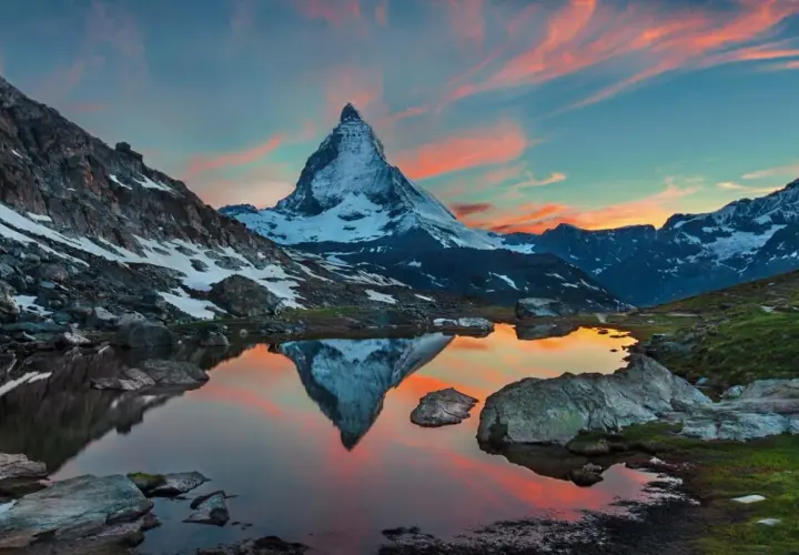 Zachód słońca nad jeziorem z odbiciem Matterhornu. Widok na wejście na Matterhorn, otoczone skalistymi zboczami i ośnieżonymi szczytami.