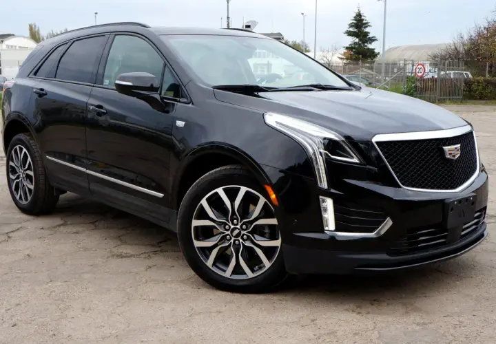 Czarny Cadillac XT5 z chromowanymi detalami i charakterystyczną atrapą chłodnicy stoi na betonowym placu.