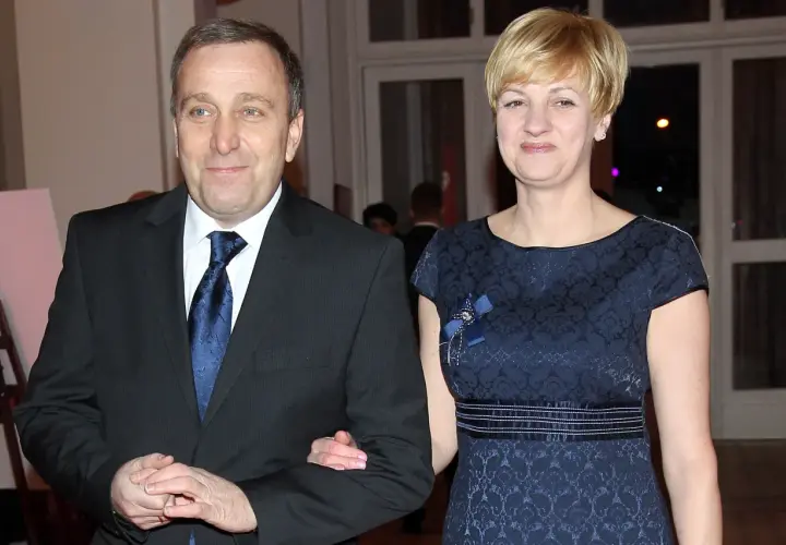 Cezary Grabarczyk z żoną, w eleganckich strojach. Może rozmawiają o swoich dzieciach i ich przyszłości.