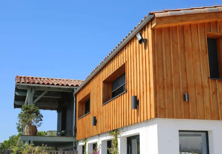 Bardage en bois naturel, un choix idéal pour l'extérieur. La maison moderne arbore des lames de bois clair sous un ciel bleu.