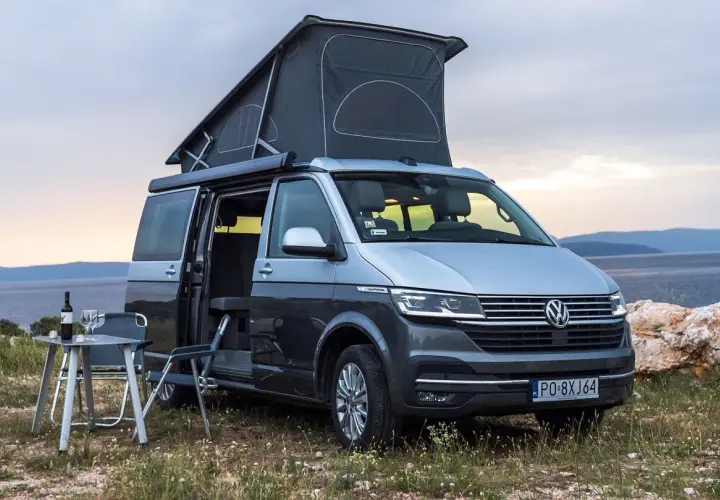 Szary kamper VW California z podniesionym dachem, idealny na wakacje. Poznaj jego wymiary i możliwości podróżnicze.