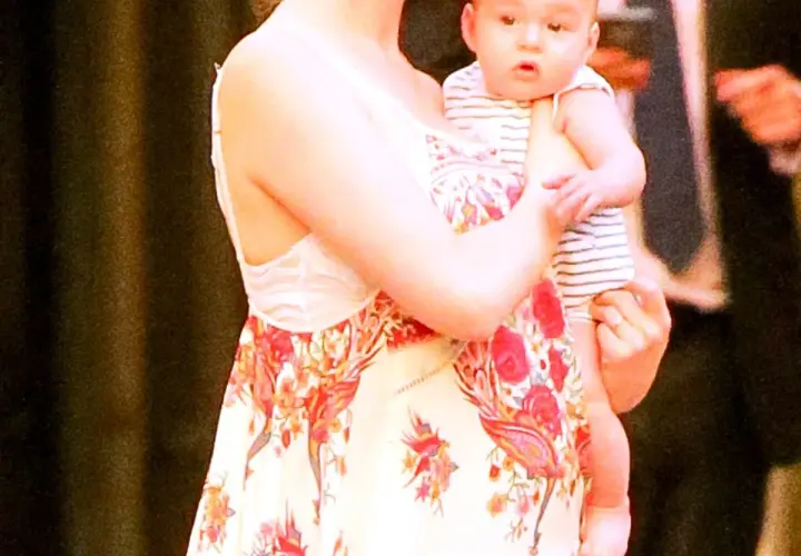 Anne Hathaway z dziećmi, tuląca niemowlę w paski.