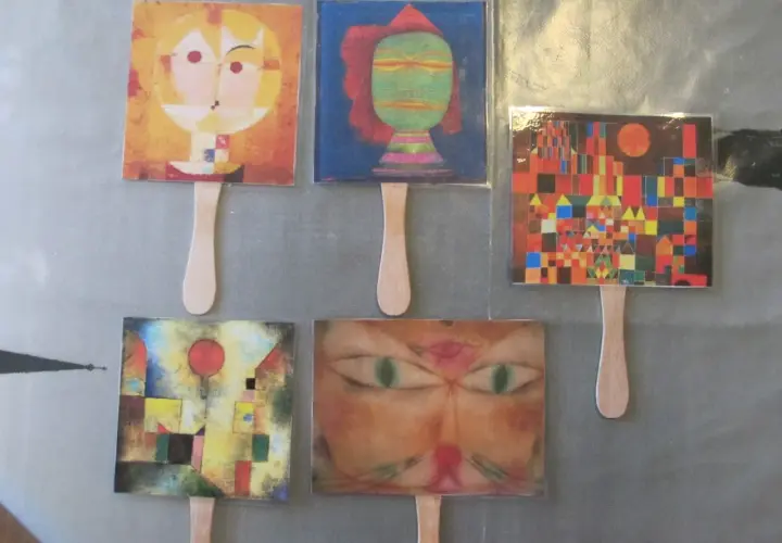 Marionetas con obras de Paul Klee para niños: rostros abstractos, un gato y un paisaje urbano colorido.