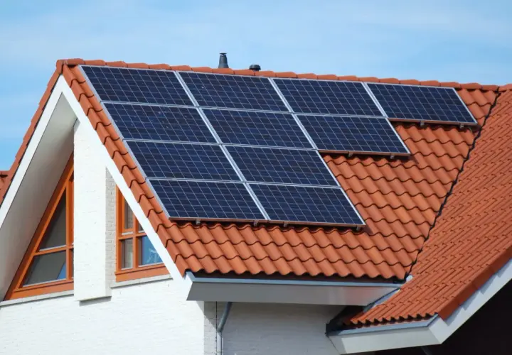 Moderne Solaranlagen auf dem roten Ziegeldach eines Hauses, bereit, Sonnenenergie zu sammeln.