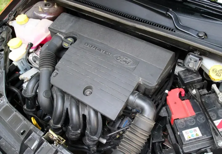 Silnik Duratec w Fordzie Fiesta Mk6. Widoczny jest czarny plastikowy kolektor, przewody i akumulator.