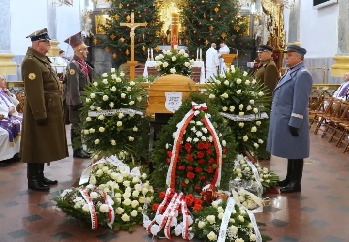 Trumna w otoczeniu wieńców, żołnierze w mundurach stoją na straży.
