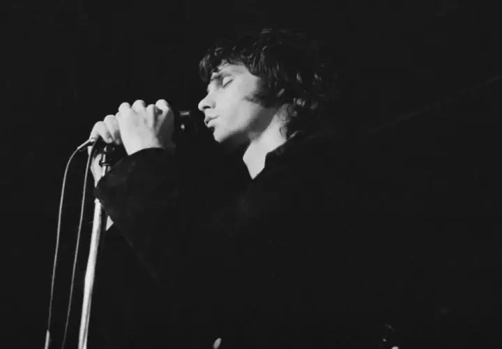 Jim Morrison z The Doors śpiewa do mikrofonu, zamykając oczy.