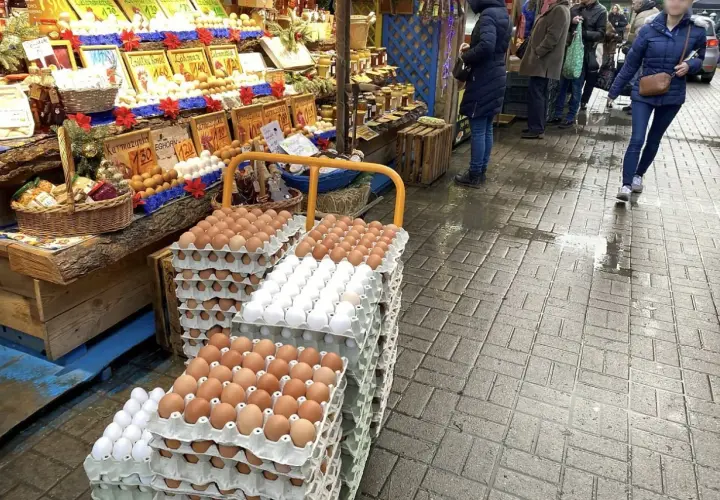 Duże stosy jajek na targu. Widać różne rodzaje i kolory, a także ceny.