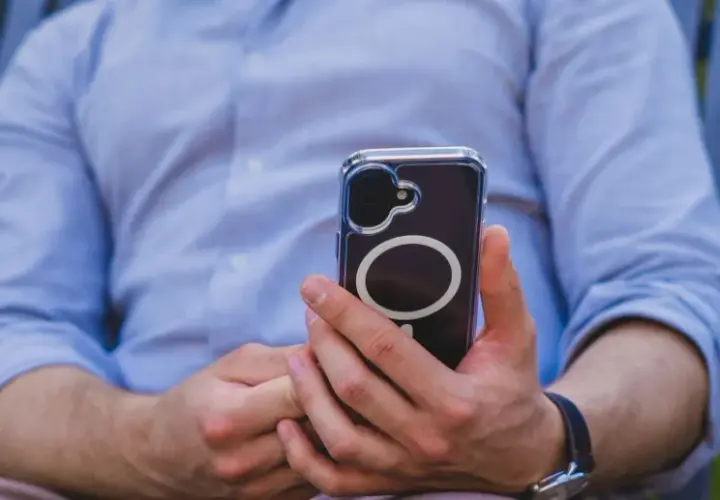 Mężczyzna w niebieskiej koszuli trzyma telefon z okrągłym wzorem. Czuć w tym nowoczesną haptykę.