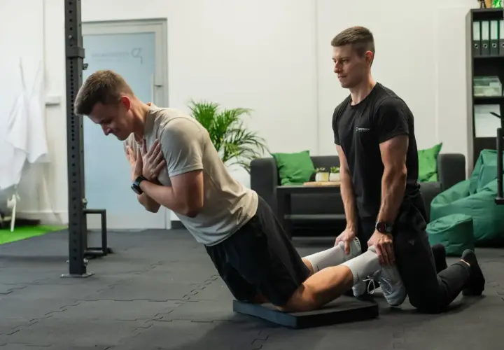 Trener pomaga w ćwiczeniu na maszynie do ćwiczeń, wspierając funkcjonalny trening siłowy.