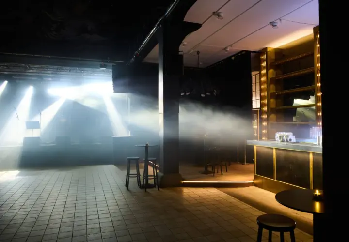 Scenljus och rök fyller lokalen på slaktkyrkan Stockholm. En bar i guld och svart syns till höger.