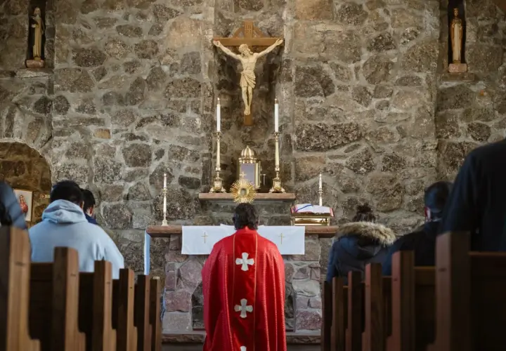 Ludzie w kościele, przed ołtarzem z krzyżem i monstrancją.