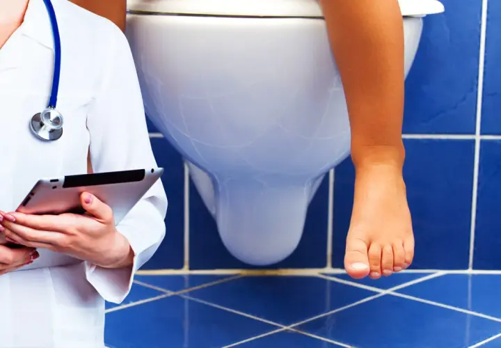 Medico con tablet osserva bambino sul water. Possibile problema di cacca bianca bambini.