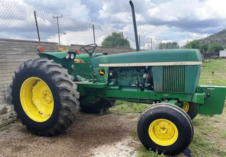 Zielony John Deere 3130 z żółtymi felgami, gotowy do pracy na polu.