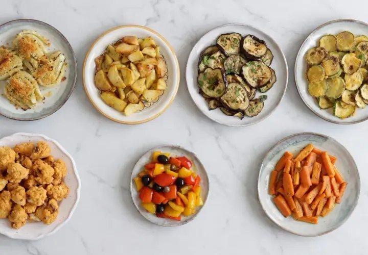 Sette piatti di verdure in friggitrice ad aria: finocchi, patate, melanzane, zucchine, cavolfiore, peperoni e carote.