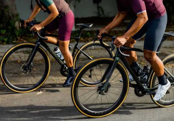 Two cyclists on road bikes, one with a blue book in their jersey pocket, showcase the value of a high-performance bike.