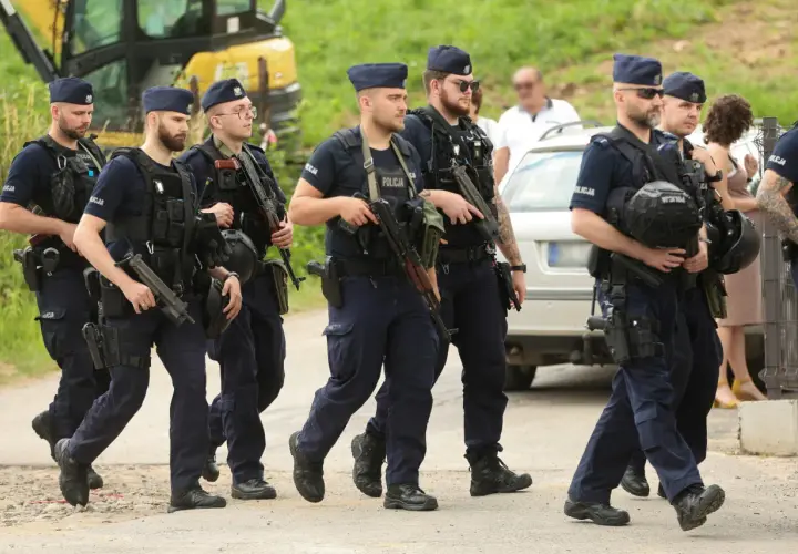 Grupa policjantów w pełnym rynsztunku, z bronią, maszeruje. To szkolenie policyjne, które przygotowuje ich do trudnych zadań.