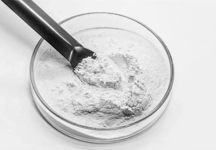 Biały proszek, prawdopodobnie kwas salicylowy jak stosować, w szklanej miseczce laboratoryjnej, nabierany metalową szpatułką.