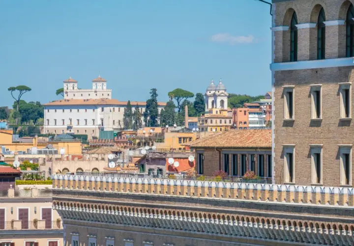 Vue panoramique de Rome, avec la Villa Médicis et ses jardins en arrière-plan, sous un ciel bleu clair.