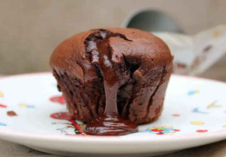 Coulant de chocolate con centro líquido y cremoso, servido en un plato decorado con globos.