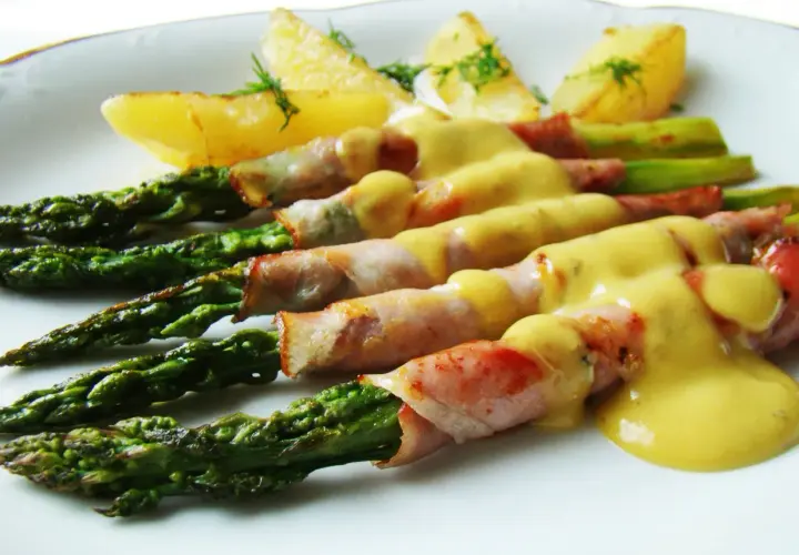 Zielone szparagi w szynce parmeńskiej, polane sosem, z pieczonymi ziemniakami. Pyszne danie.