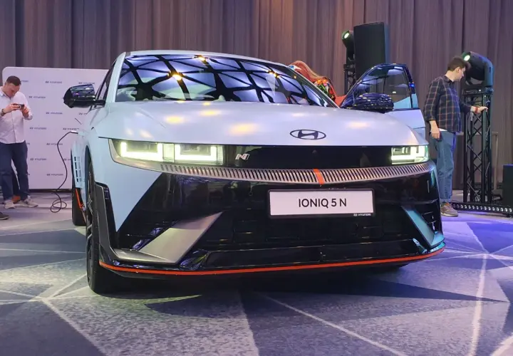 Hyundai IONIQ 5 N na prezentacji, z otwartymi drzwiami, w tle ludzie i logo Hyundai.