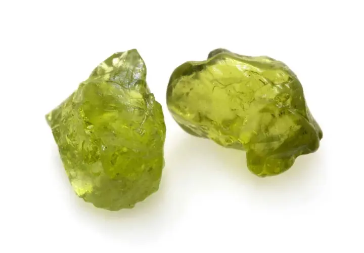 Zwei rohe Peridot-Kristalle in leuchtendem Grün. Ihre natürliche **Peridot Wirkung** soll angeblich das Herz öffnen und positive Energie fördern.