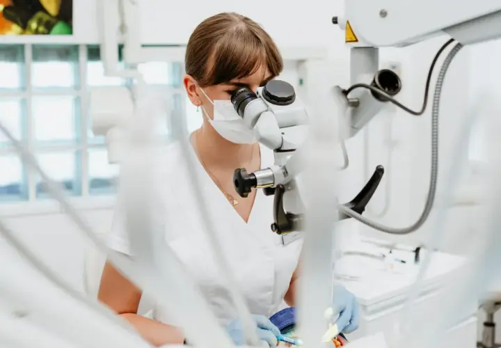 Dentystka pod mikroskopem. Zastanawiasz się, ile kosztuje wypełnienie zęba? Precyzyjna praca stomatologa.