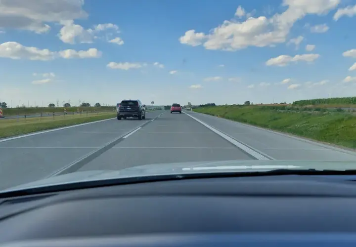 Widok z samochodu na autostradzie. Widać inne pojazdy i znaki ograniczające prędkość do 80 km/h.