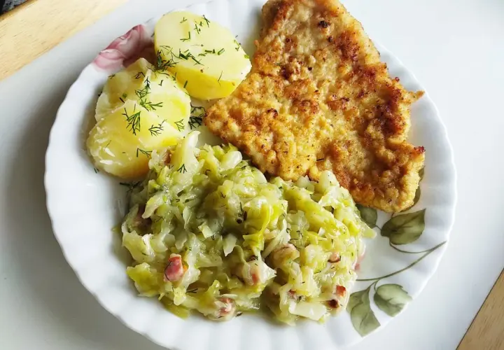 Młoda kapusta zasmażana z boczkiem, podana z ziemniakami i kotletem. Pyszny, domowy obiad.