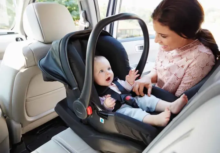 Mama z uśmiechem obserwuje dziecko w foteliku samochodowym. To jeden z rodzajów fotelików samochodowych, zapewniający bezpieczeństwo najmłodszych.