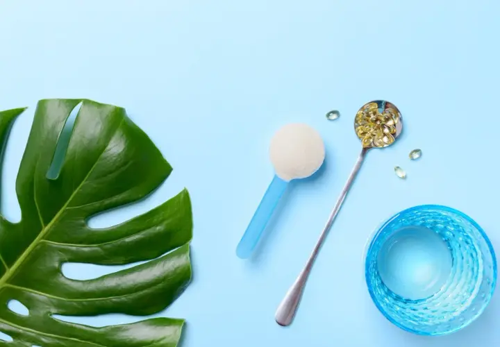 Grünes Monstera-Blatt, Löffel mit Kapseln, Pulver und Glas Wasser. Alles für die gleiche Wirkung.