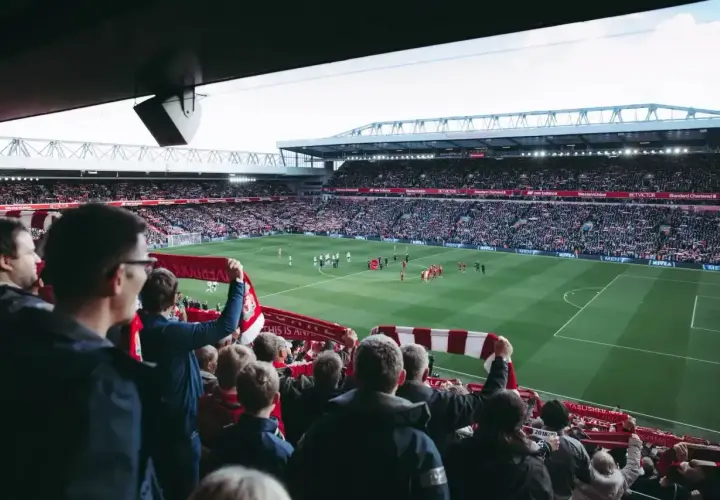Kibice na stadionie z szalikami, czekają na wznowienie gry. Zastanawiają się, ile trwa przerwa w meczu.