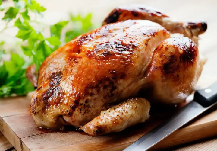 Un délicieux poulet rôti doré sur une planche en bois, prêt à être dégusté. Quel vin avec poulet rôti ? Un blanc fruité ou un rouge léger serait parfait.