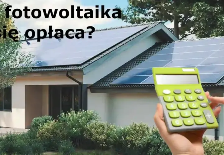 Dwie ręce trzymają kalkulator obok domu z panelami fotowoltaicznymi na dachu. Czy fotowoltaika się opłaca?