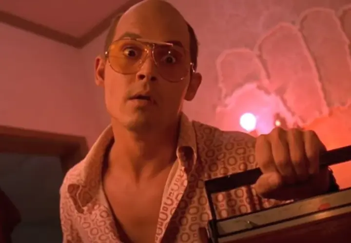 Raoul Duke z Las Vegas Parano, w okularach i wzorzystej koszuli, trzyma magnetofon.