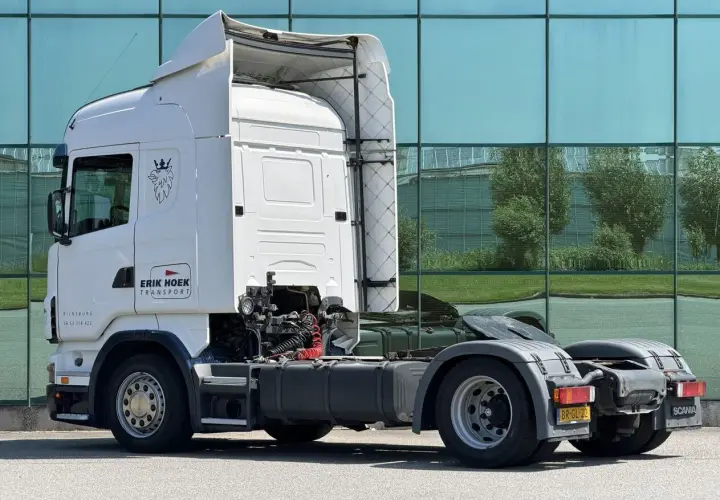 Biała Scania R420 z logo "Erik Hoek Transport" stoi przed nowoczesnym budynkiem z zielonymi oknami.