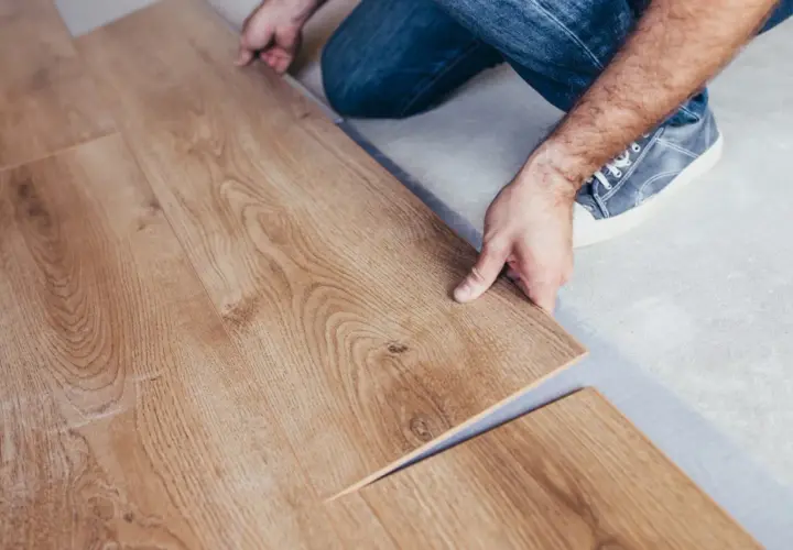 Installazione di un nuovo pavimento in laminare parquet. Le assi in legno chiaro vengono posate con cura.