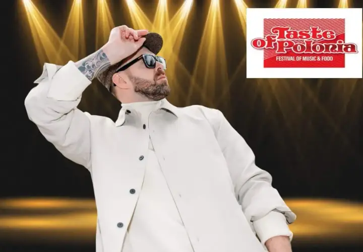 Grzegorz Hyży wstaje na scenie Taste of Polonia, w białej kurtce i czapce, w blasku reflektorów.