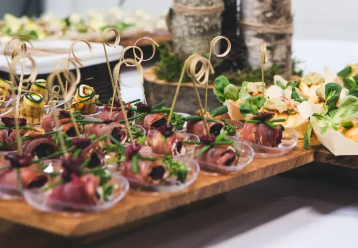 Eleganckie przekąski na desce, idealne na catering we Wrocławiu na imprezy. Roladki z szynki, rolmopsy z cukinii i inne smakołyki.