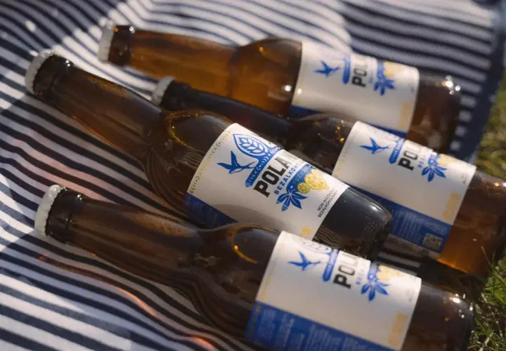 Butelki piwa bezalkoholowego POLAN leżą na kocu. Czy piwo zero ma alkohol? Nie, to piwo jest bezalkoholowe.